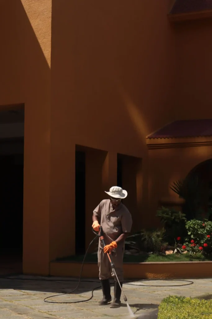 Worker in protective gear power cleaning stone exterior